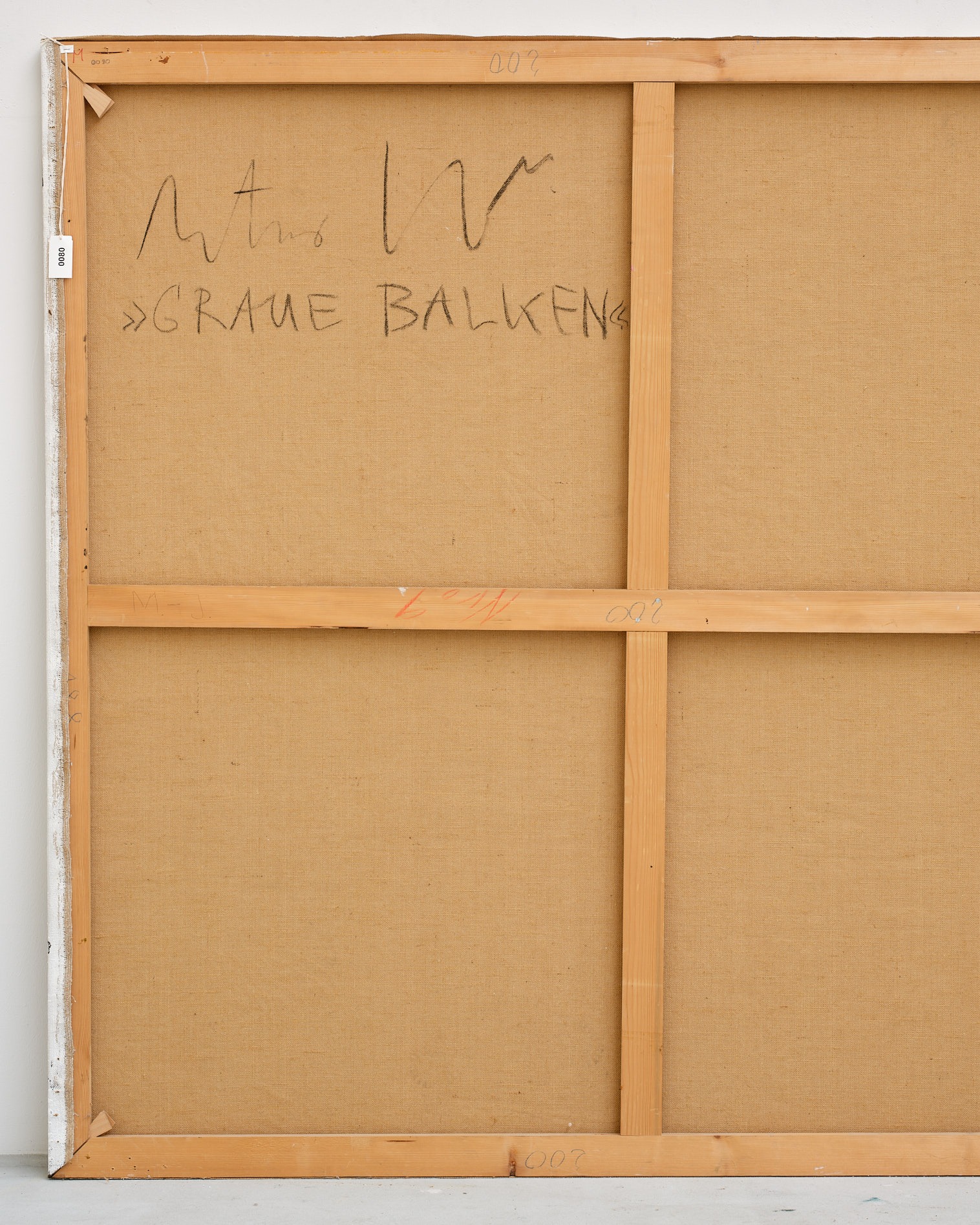 Dieser Alternativtext wurde KI-generiert: Das Bild zeigt die Rückseite einer Leinwand. Auf dem braunen Stoff sind einige Schriftzüge und Nummern in dunkler Farbe zu erkennen.