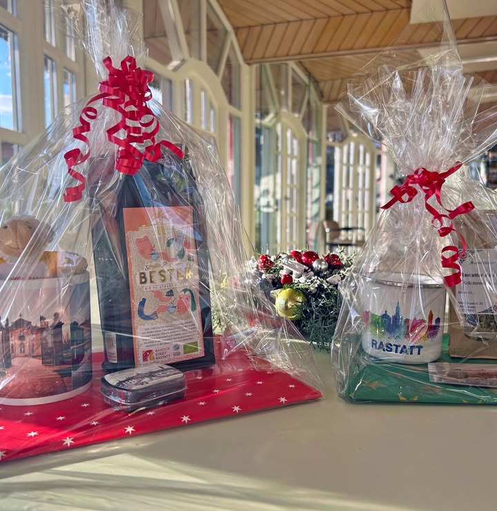 Dieser Alternativtext wurde KI-generiert: Mehrere festlich verpackte Geschenke stehen auf einer grünen Unterlage vor einem verschwommenen Hintergrund. Die Geschenke sind mit Schleifen und weihnachtlichen Dekorationen verziert.