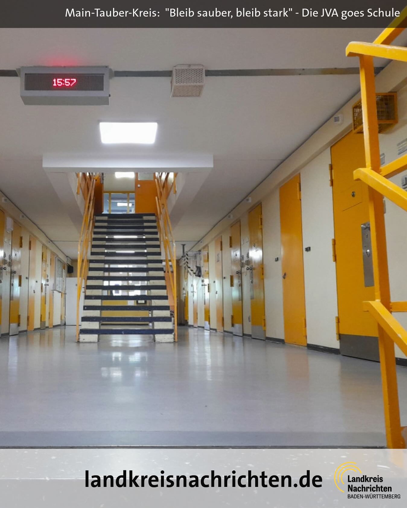 Dieser Alternativtext wurde KI-generiert: Ein Innenraum mit einer Treppe, die zu einem höheren Stockwerk führt. An der Wand befindet sich eine digitale Uhr und ein Logo im unteren Bildbereich.