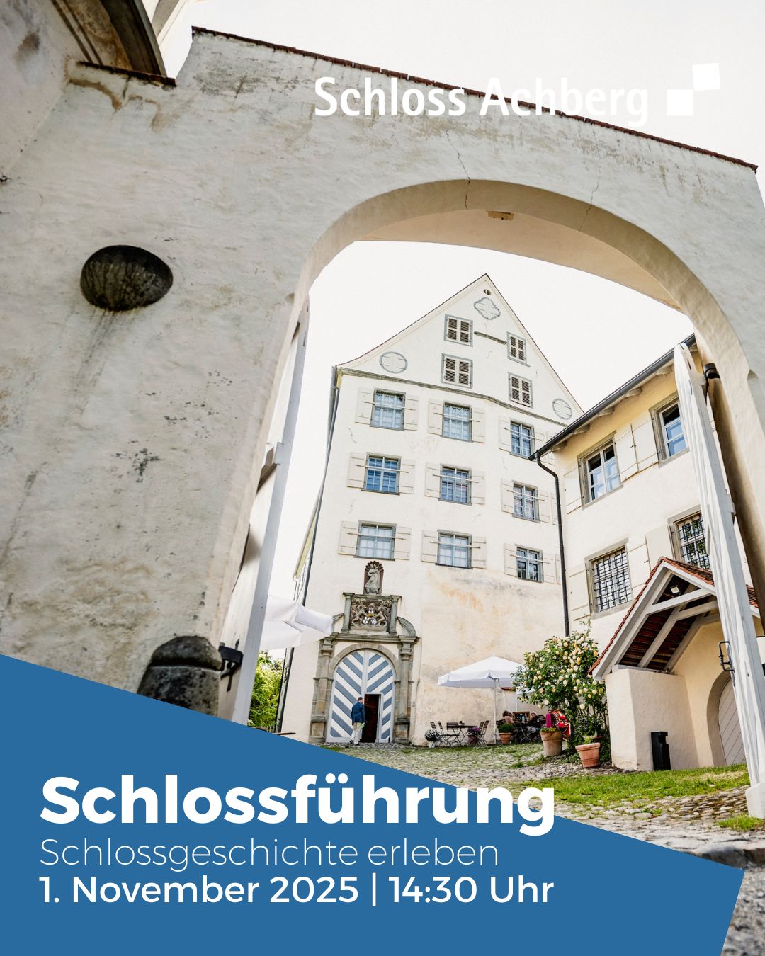 Dieser Alternativtext wurde KI-generiert: Ein Blick durch einen Torbogen auf ein helles Gebäude mit mehreren Fenstern. Im Vordergrund befindet sich ein blaues Werbeplakat für eine Schlossführung.