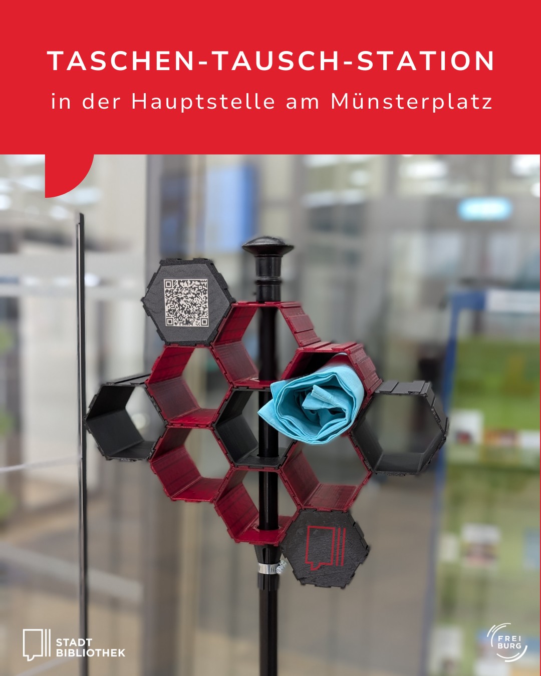 Dieser Alternativtext wurde KI-generiert: Ein farbiges, strukturiertes Objekt steht vor einer verschwommenen modernen Innenarchitektur. Es enthält mehrere sechseckige Fächer, in denen Tücher liegen.
