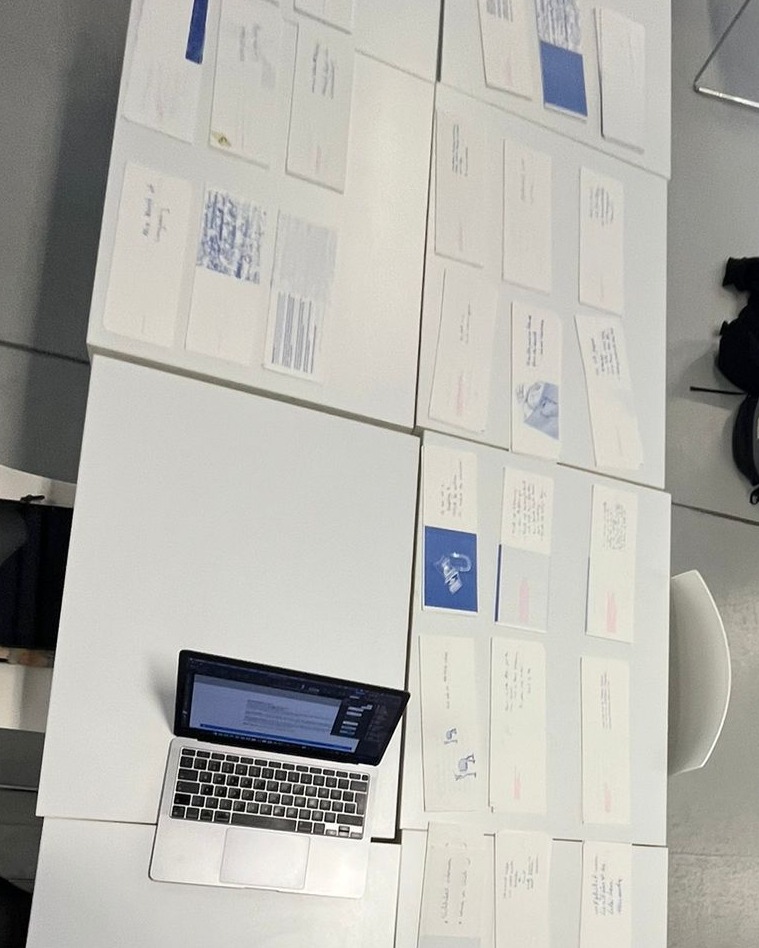 Dieser Alternativtext wurde KI-generiert: Ein Tisch ist mit vielen Papieren und einem geöffneten Laptop bedeckt. Die Papiere enthalten handschriftliche Notizen und einige Bilder.