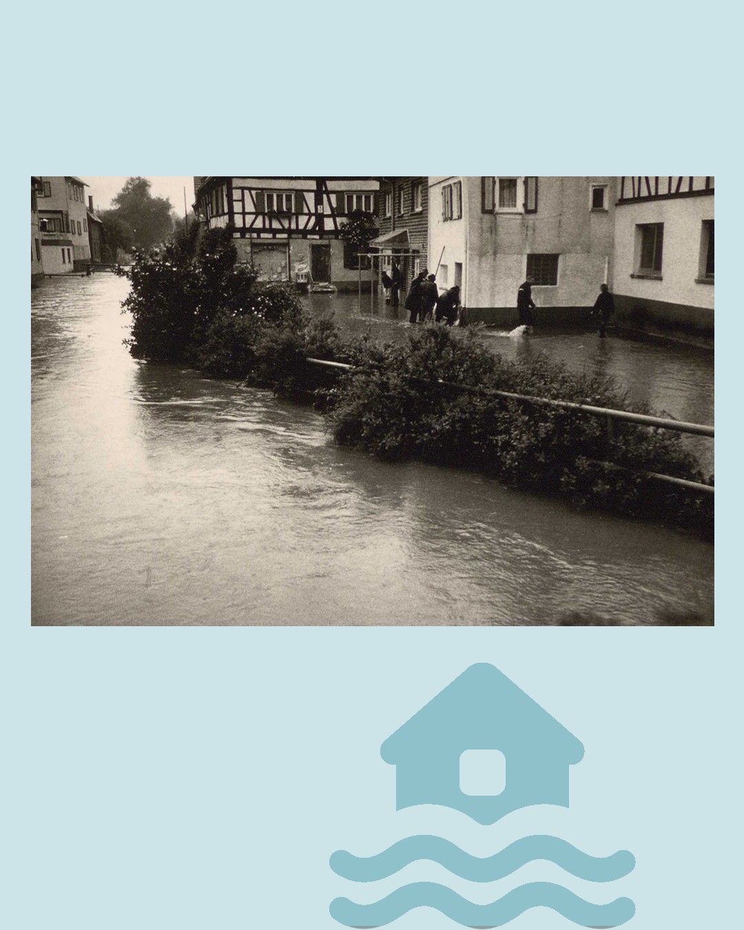 Schwarz-Weiß-Foto einer überfluteten Straße, auf der mehrere Personen durch das Wasser waten, flankiert von Büschen im Vordergrund und Gebäuden im Hintergrund. Darunter befindet sich ein blaues Symbol eines Hauses, das von Wellen umspült wird. (KI-Alternativtext)