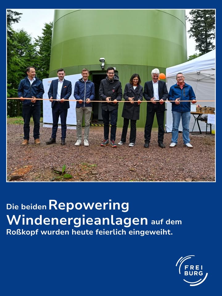 Dieser Alternativtext wurde KI-generiert: Eine Gruppe von Personen steht vor einem großen, blauen Silo und einem weißen Zelt. Sie scheinen an einer feierlichen Veranstaltung teilzunehmen.