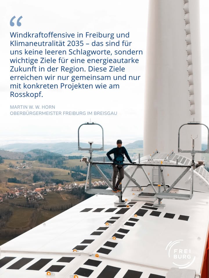 Dieser Alternativtext wurde KI-generiert: Ein schwarz-weißes Bild zeigt eine Person, die auf einer Struktur in großer Höhe arbeitet. Im Hintergrund ist eine städtische Landschaft und am unteren Rand ein Logo zu sehen.