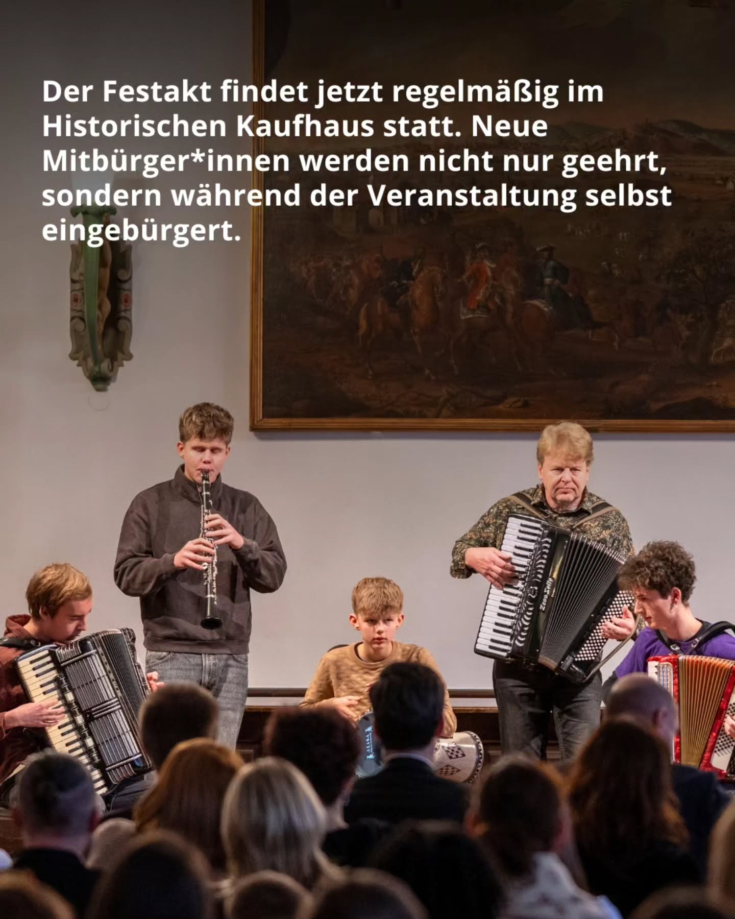 Dieser Alternativtext wurde KI-generiert: Ein Innenraum mit Personen, die Musikinstrumente spielen. Im Hintergrund sind weitere Personen und eine festliche Dekoration zu erkennen.