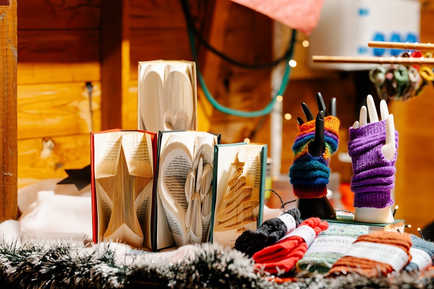 Buchkünstlerarbeiten in Herz-, Stern- und Tannenbaumform sowie handgestrickte Fingerhandschuhe werden auf einem Marktstand präsentiert.