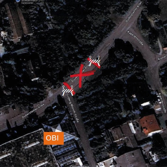 Dieser Alternativtext wurde KI-generiert: Luftaufnahme einer Straße mit eingezeichnetem rotem Pfad und Markierungen. Im unteren Bildrand ist ein orangefarbenes Schild mit Aufschrift zu sehen.