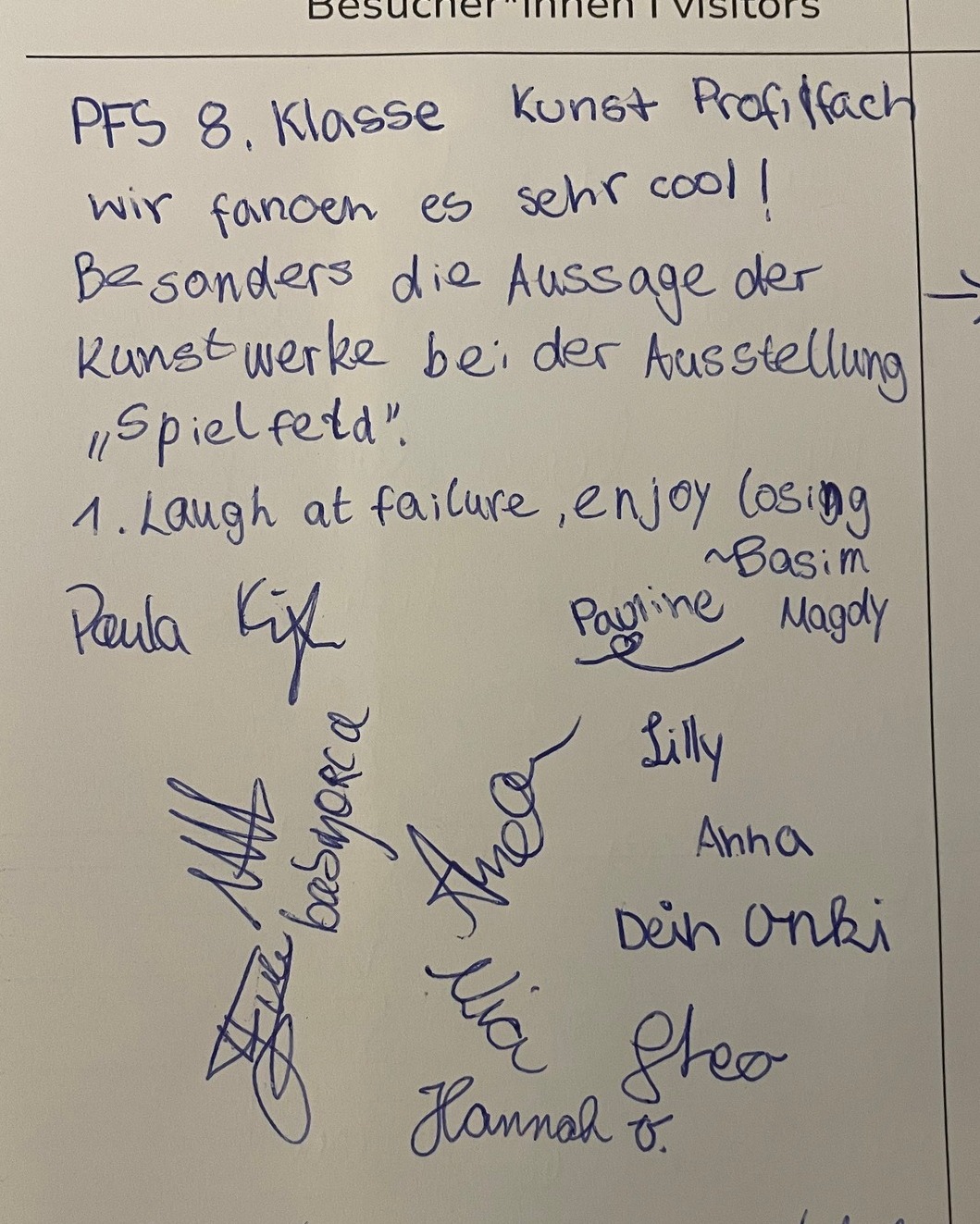 Handgeschriebene Notiz von Schülern der PFS 8. Klasse Kunst Profilfach, die die Ausstellung „Spielfeld“ loben, mit Unterschriften und einem Zitat: „Laugh at failure, enjoy losing“. (KI-Alternativtext)