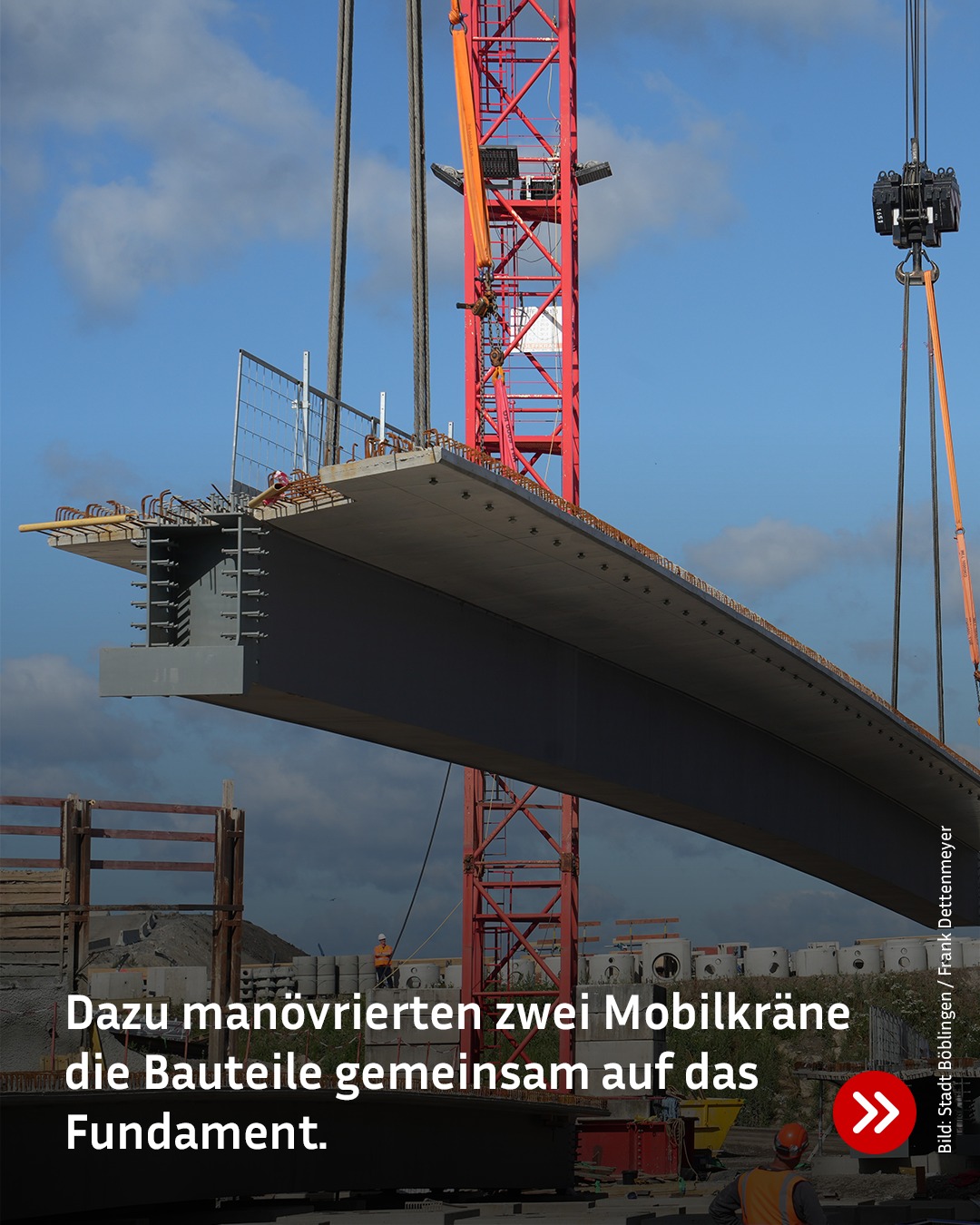 Zwei Mobilkräne heben gemeinsam ein großes Betonbauteil auf ein Fundament. Im Hintergrund sind weitere Baustellenmaterialien und Personen in Warnwesten zu sehen. Der Himmel ist blau mit einigen Wolken. (KI-Alternativtext)