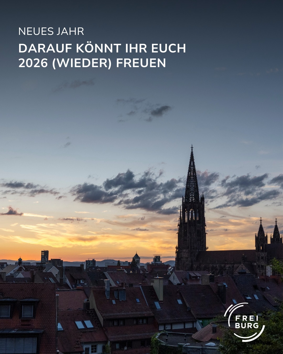 Dieser Alternativtext wurde KI-generiert: Ein Stadtbild bei Sonnenuntergang mit einem hohen Kirchturm im Zentrum. Der Text "Neues Jahr darauf könnt ihr euch 2026 (wieder) freuen" ist auf dem Bild zu sehen.