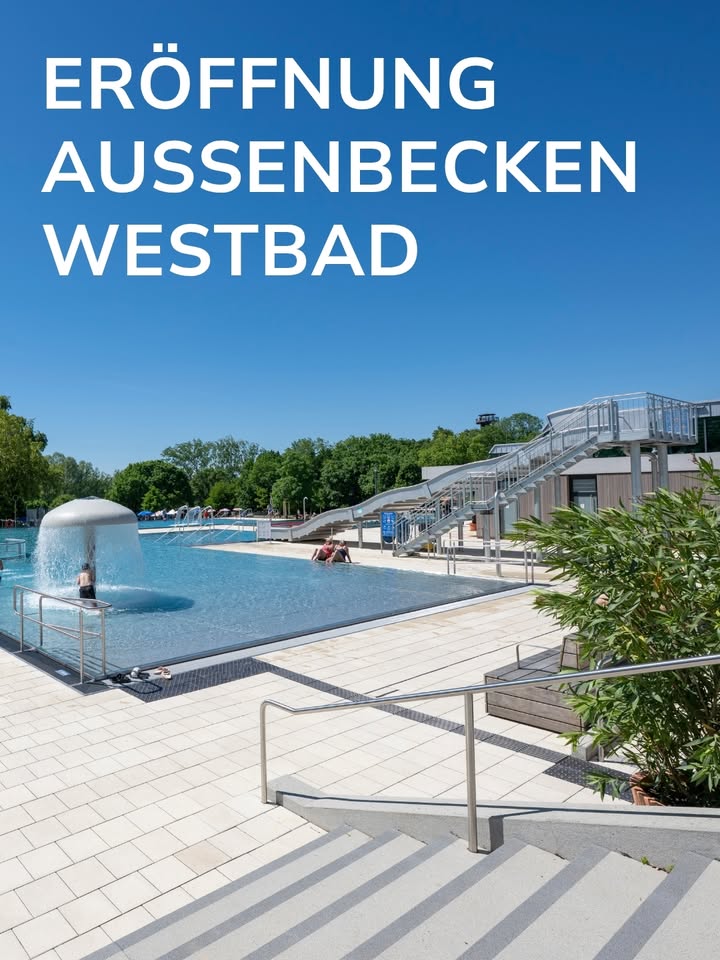 Oben im Bild steht in großen weißen Buchstaben auf blauem Himmel: ERÖFFNUNG AUSSENBECKEN WESTBAD. Im Vordergrund führen Treppenstufen mit Geländer hinunter zu einem großen Außenpool, in dem Personen baden. Links im Wasser ist eine Fontäne zu sehen, rechts im Hintergrund führt eine große Metalltreppe zu einer erhöhten Plattform. (KI-Alternativtext)