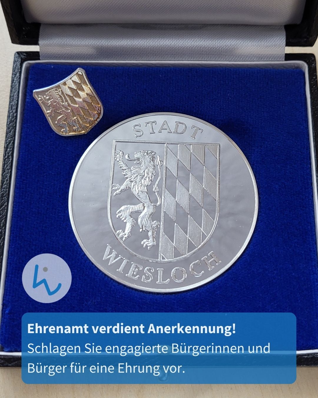 Silberne Medaille mit dem Wappen der Stadt Wiesloch und einem kleinen goldenen Wappenabzeichen, präsentiert in einem blauen Samtkästchen. Darunter der Text: „Ehrenamt verdient Anerkennung! Schlagen Sie engagierte Bürgerinnen und Bürger für eine Ehrung vor.“ (KI-Alternativtext)