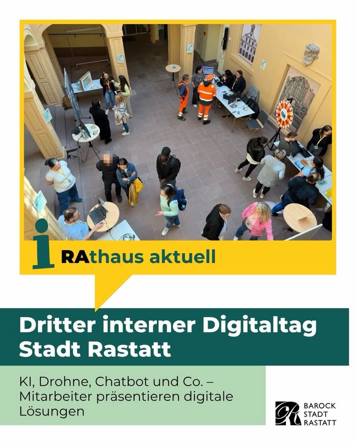 Mehrere Personen interagieren in einem hellen Innenraum mit Informationsständen, Laptops und einem Glücksrad; darunter Text: „Dritter interner Digitaltag Stadt Rastatt – KI, Drohne, Chatbot und Co. – Mitarbeiter präsentieren digitale Lösungen“. (KI-Alternativtext)