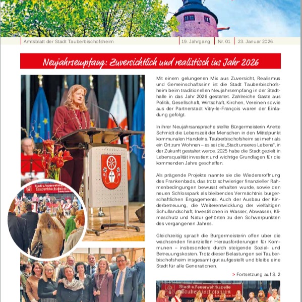 Dieser Alternativtext wurde KI-generiert: Schwarz-weißes Bild einer festlichen Rede oder Ansprache. Im Hintergrund ist ein Banner mit Text zu sehen, während eine Person am Rednerpult steht.