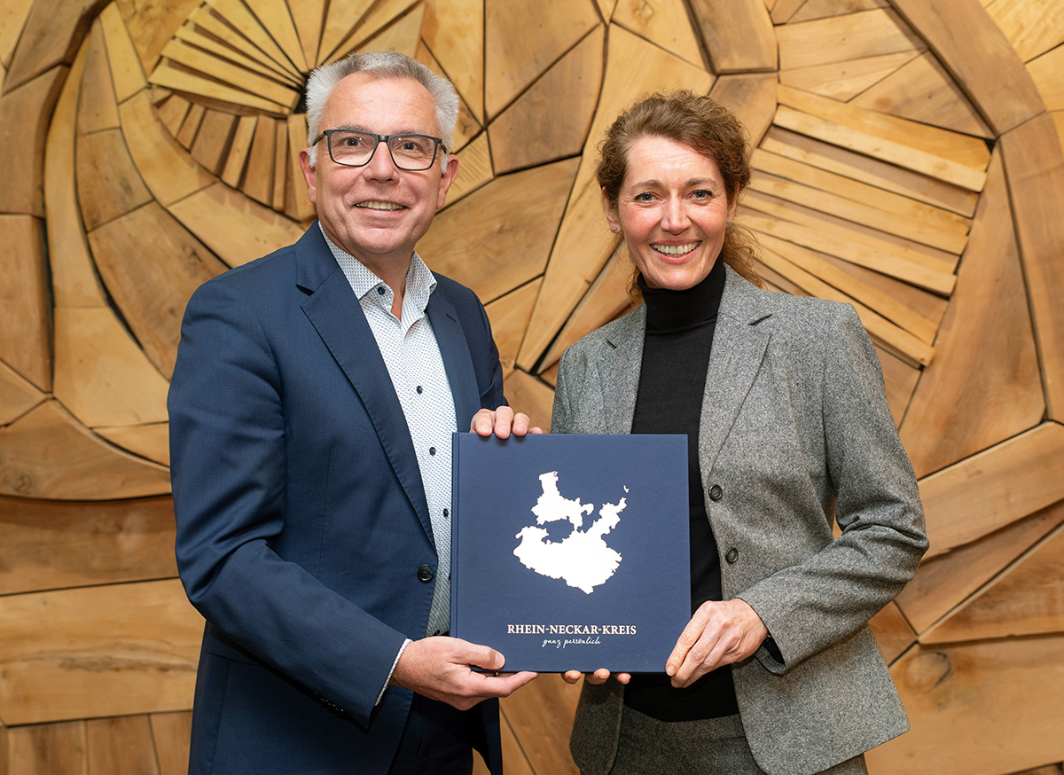 Landrat Stefan Dallinger und die Verlagsmitarbeiterin präsentieren das neue Buch.