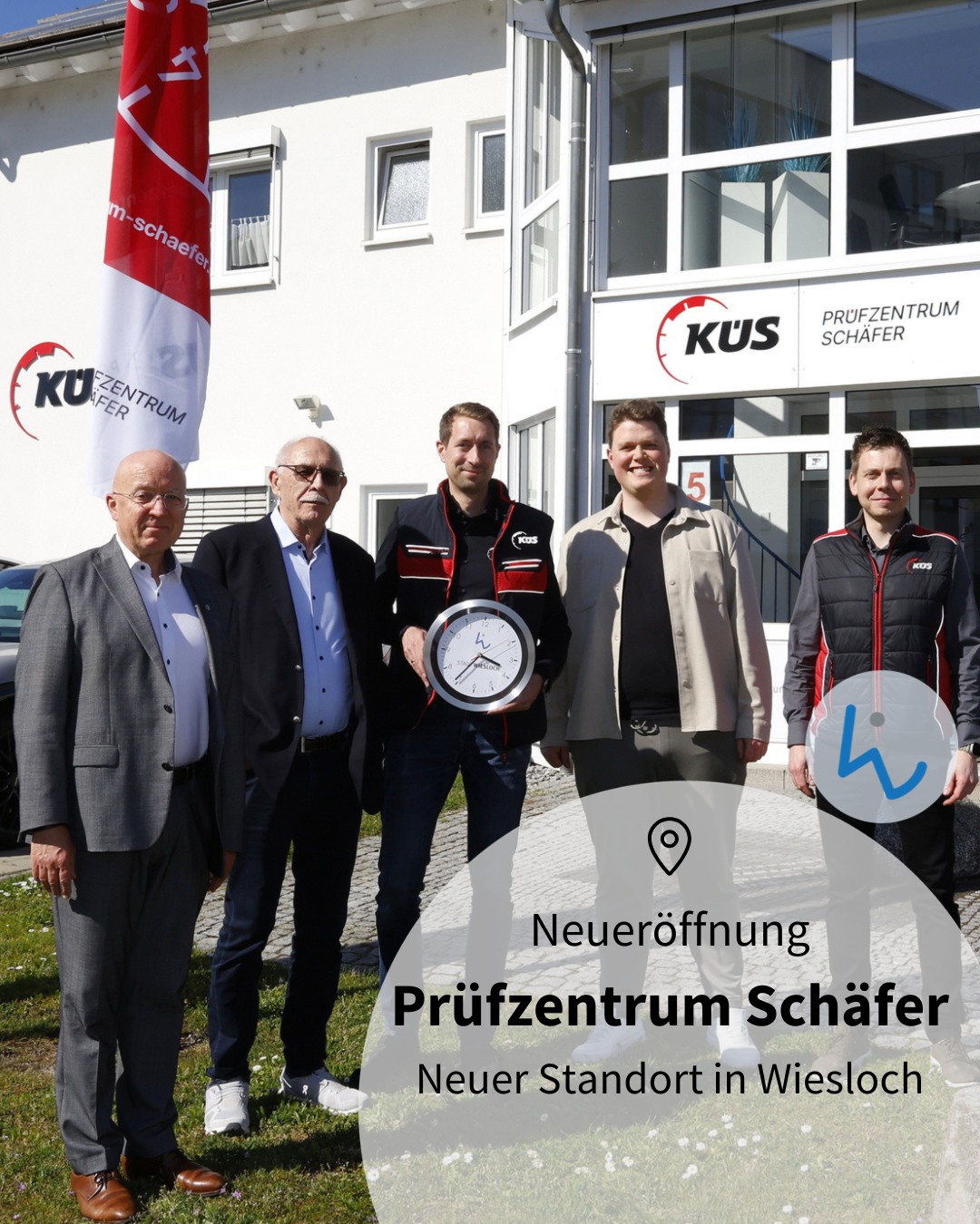 Dieser Alternativtext wurde KI-generiert: Eine farbige Aufnahme zeigt eine Gruppe von Menschen vor einem Gebäude. Im Vordergrund hält jemand ein großes rundes Objekt, während ein Banner im Hintergrund eine Eröffnungsankündigung zeigt.