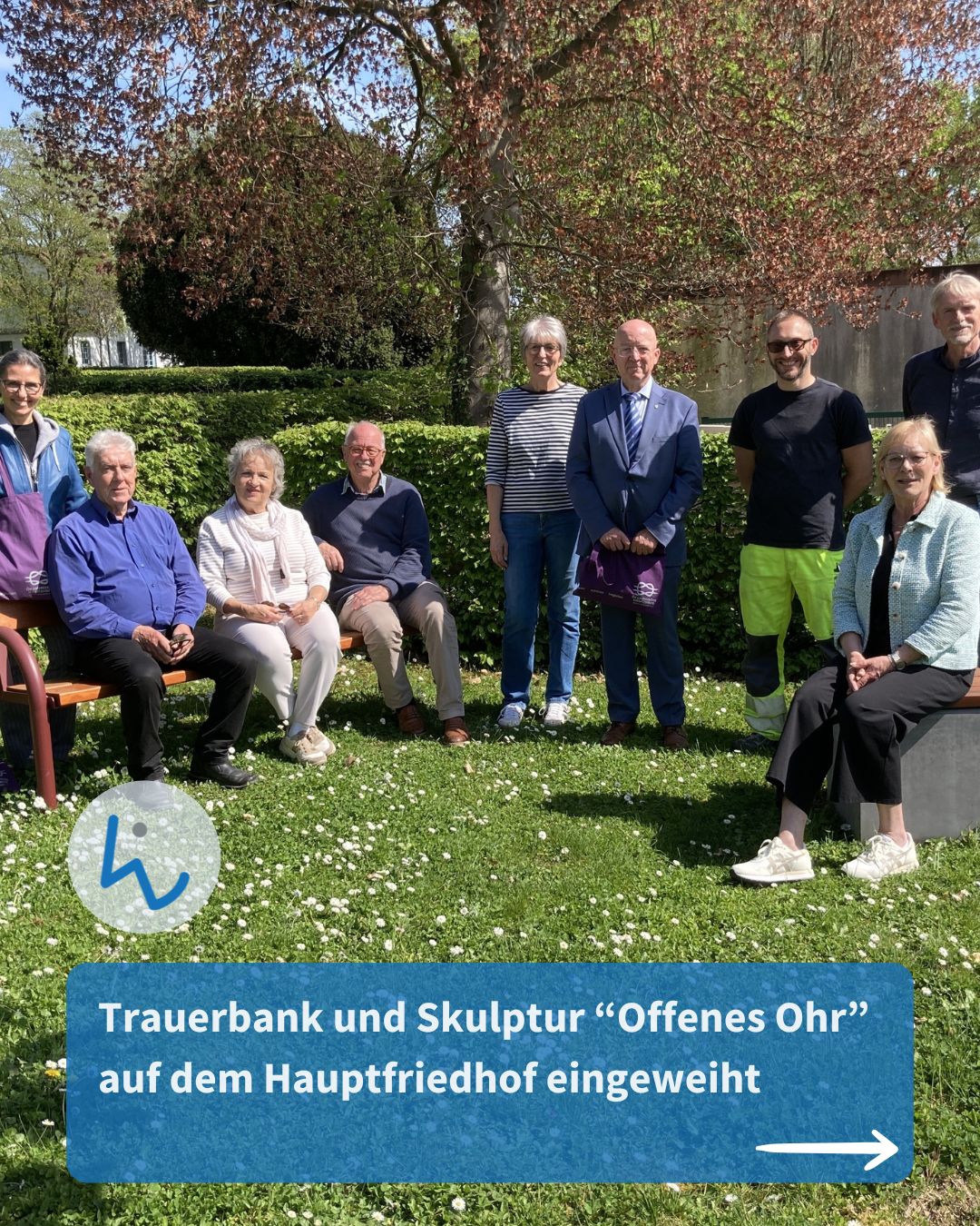 Dieser Alternativtext wurde KI-generiert: Eine Gruppe von Menschen steht und sitzt auf einer gepflegten Grünfläche. Im Hintergrund befindet sich eine grüne Hecke und eine Mauer.