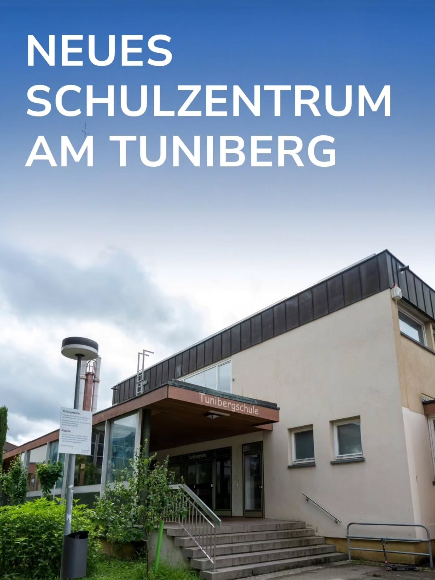 Großer weißer Schriftzug „NEUES SCHULZENTRUM AM TUNIBERG“ vor blauem Himmel. Darunter ein modernes, hellfarbenes Schulgebäude mit einer Treppe zum Eingang, über dem die Aufschrift „Tunibergschule“ zu lesen ist. (KI-Alternativtext)