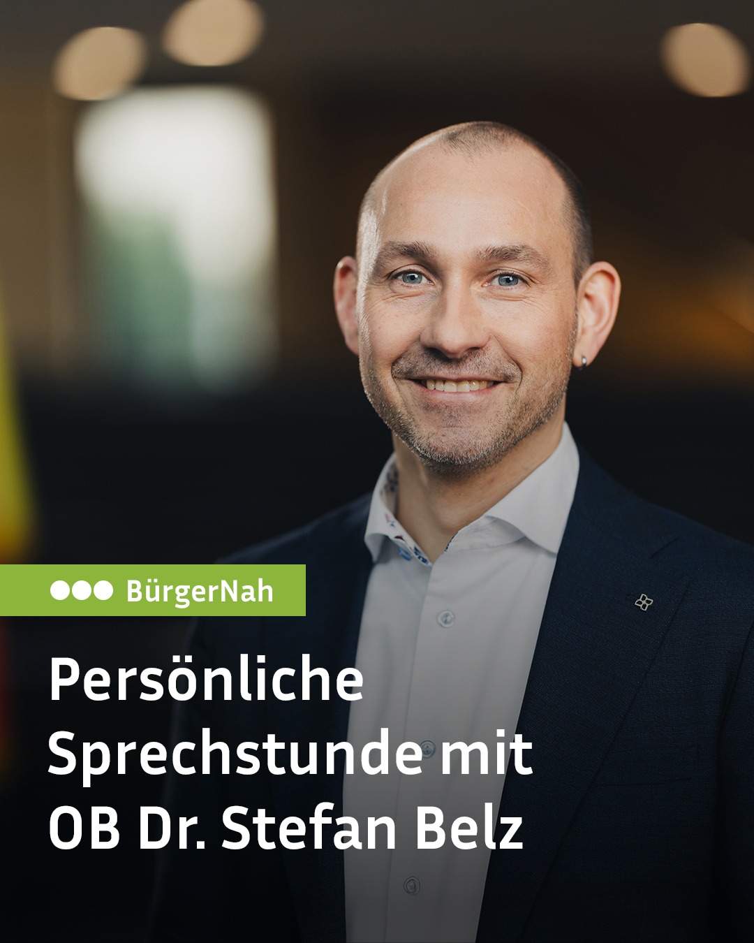 Porträt einer lächelnden Person in dunklem Anzug mit hellem Hemd vor unscharfem Hintergrund. Grüner Balken oben links zeigt drei Punkte und den Schriftzug "BürgerNah". Darunter steht der weiße Text: "Persönliche Sprechstunde mit OB Dr. Stefan Belz". (KI-Alternativtext)