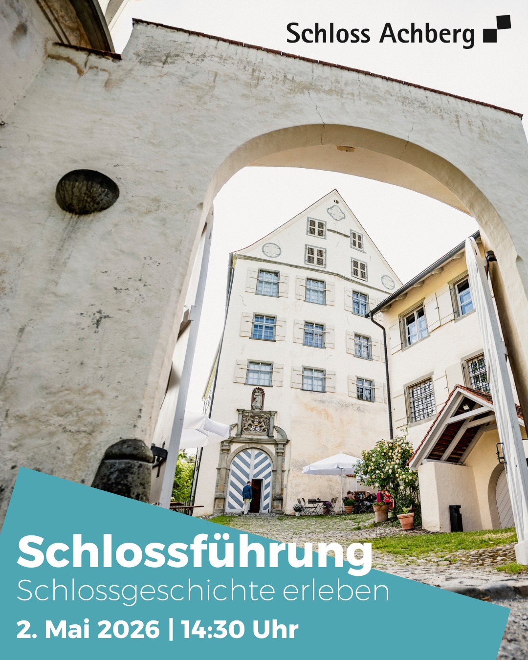 Dieser Alternativtext wurde KI-generiert: Ein Gebäude mit vielen Fenstern ist durch einen Bogen zu sehen. Ein farbiges Banner im Vordergrund kündigt eine Schlossführung an.