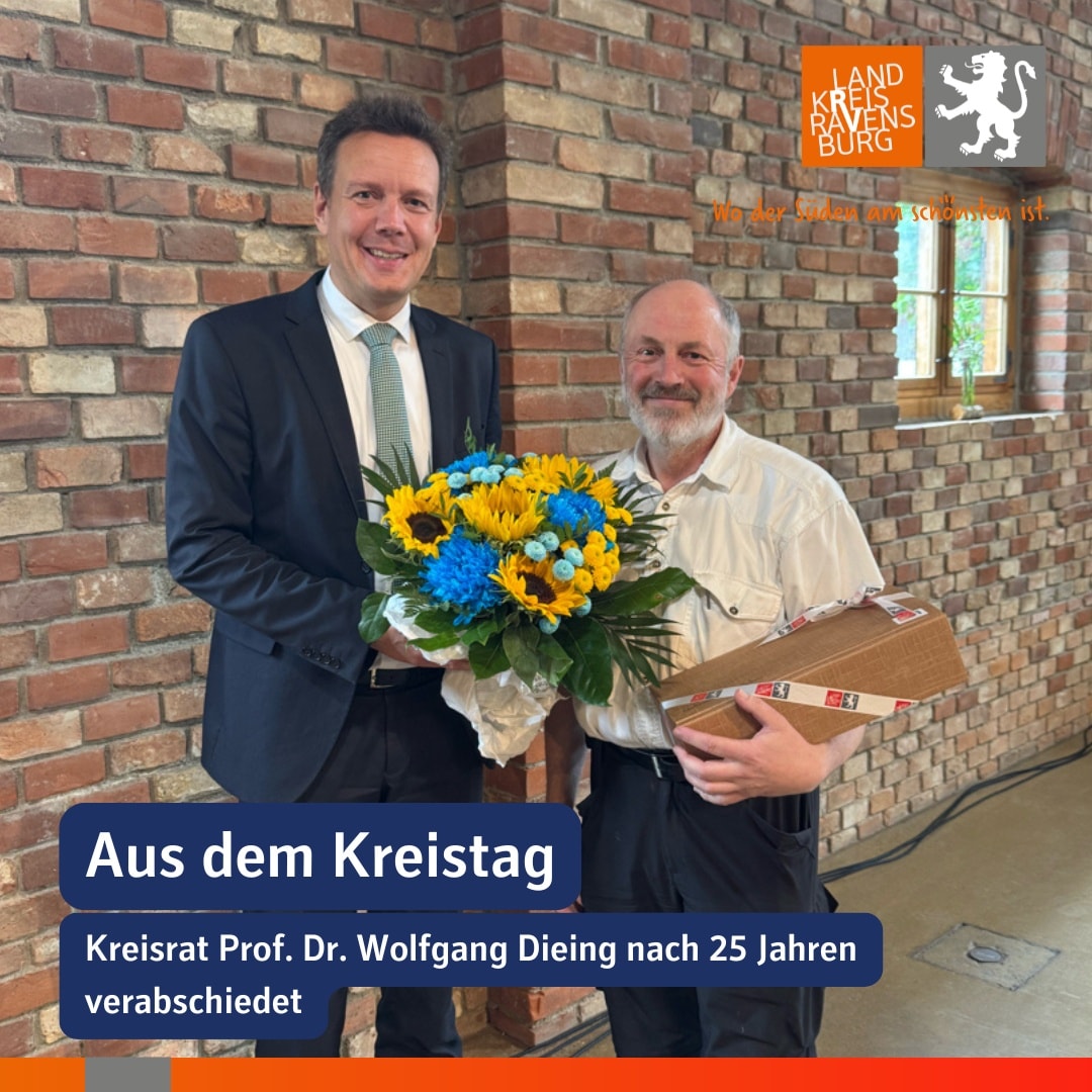 Zwei Personen stehen vor einer Ziegelwand. Eine Person hält einen Blumenstrauß, die andere eine Schachtel.