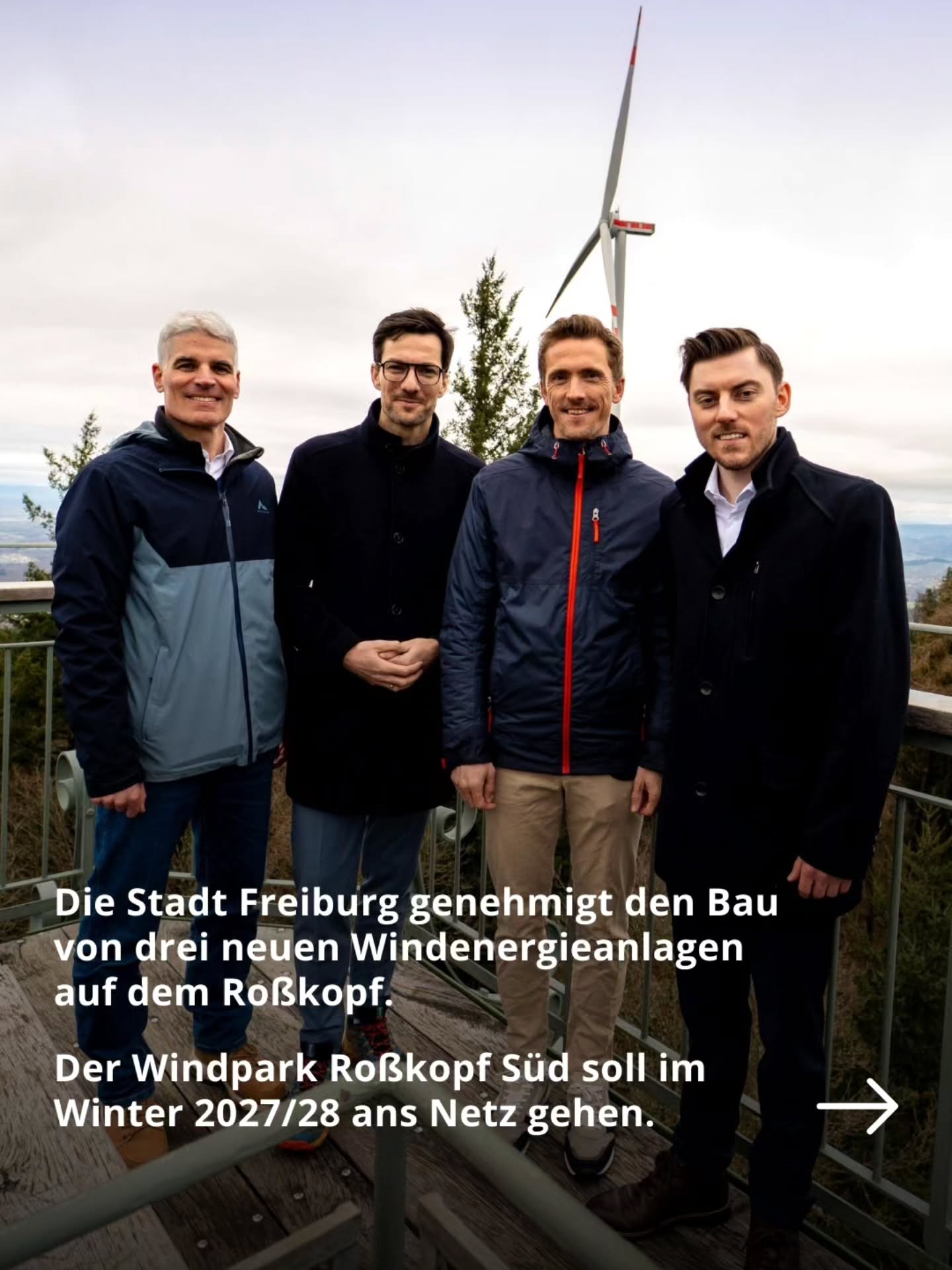 Dieser Alternativtext wurde KI-generiert: Eine Gruppe von vier Personen steht im Freien vor einem Hügel mit Windrädern im Hintergrund. Im unteren Bildbereich befindet sich ein Text über die Genehmigung von Windenergieanlagen.
