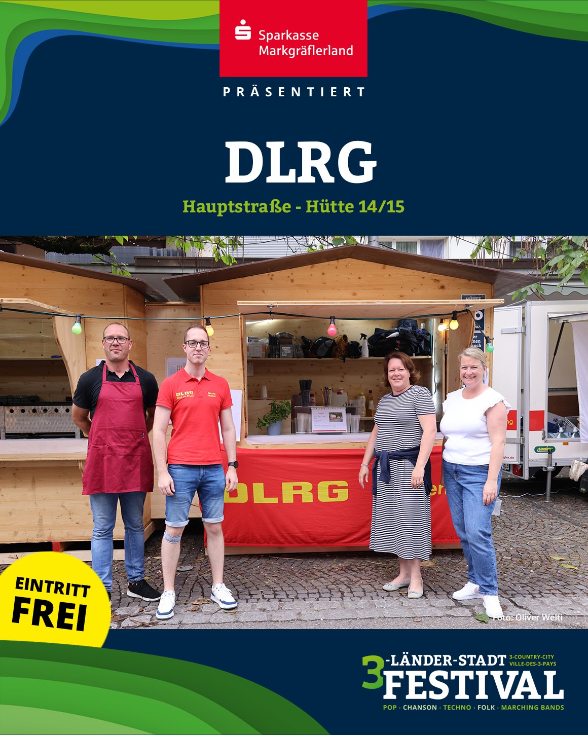 Eine Gruppe von Personen steht vor einem Stand mit der Aufschrift DLRG. Im Vordergrund befindet sich ein Schild mit der Aufschrift 'Eintritt Frei'.