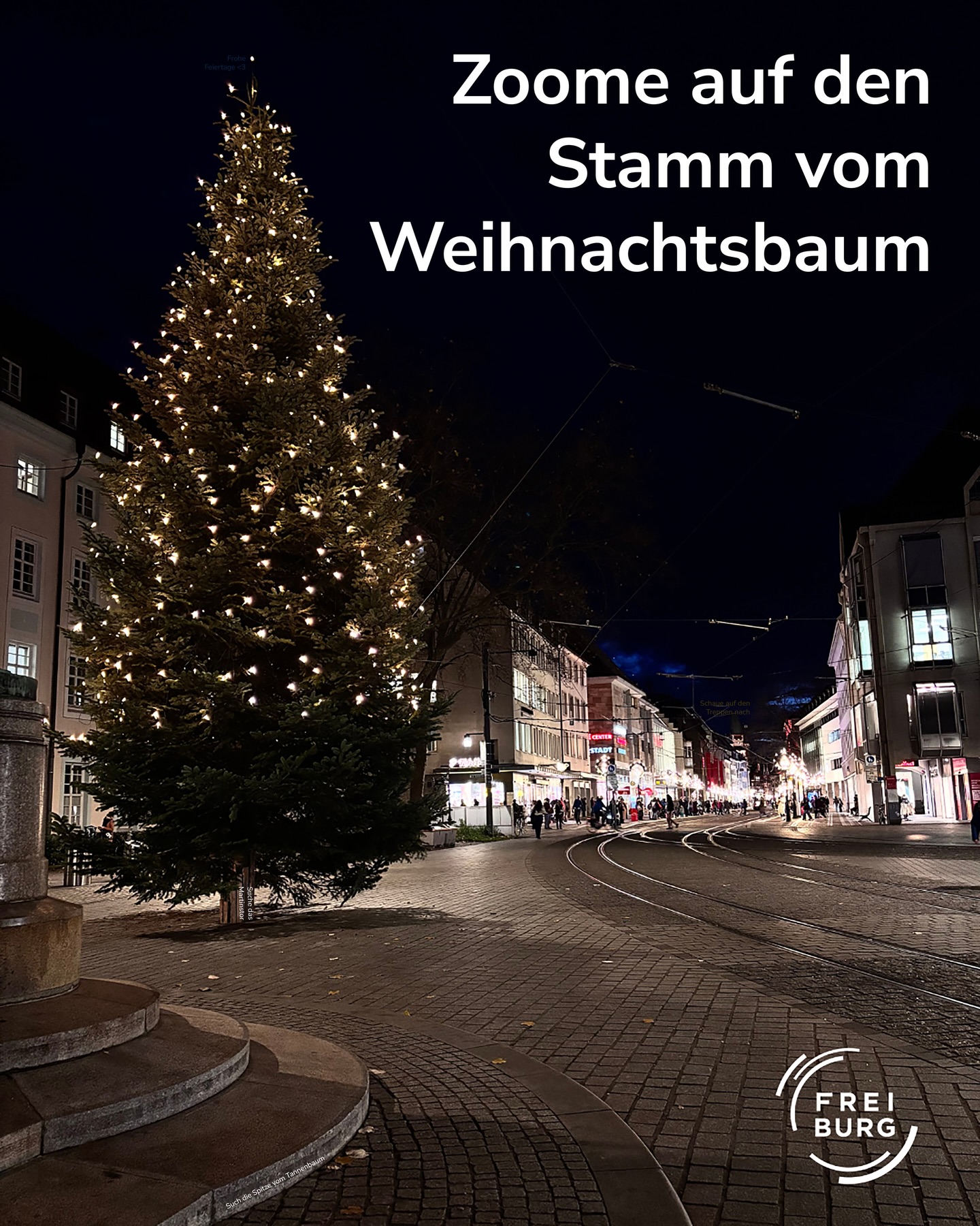 Dieser Alternativtext wurde KI-generiert: Ein beleuchteter Weihnachtsbaum steht vor einer Straßenszene in der Nacht. Im Hintergrund sind Gebäude und Straßenlaternen zu sehen.
