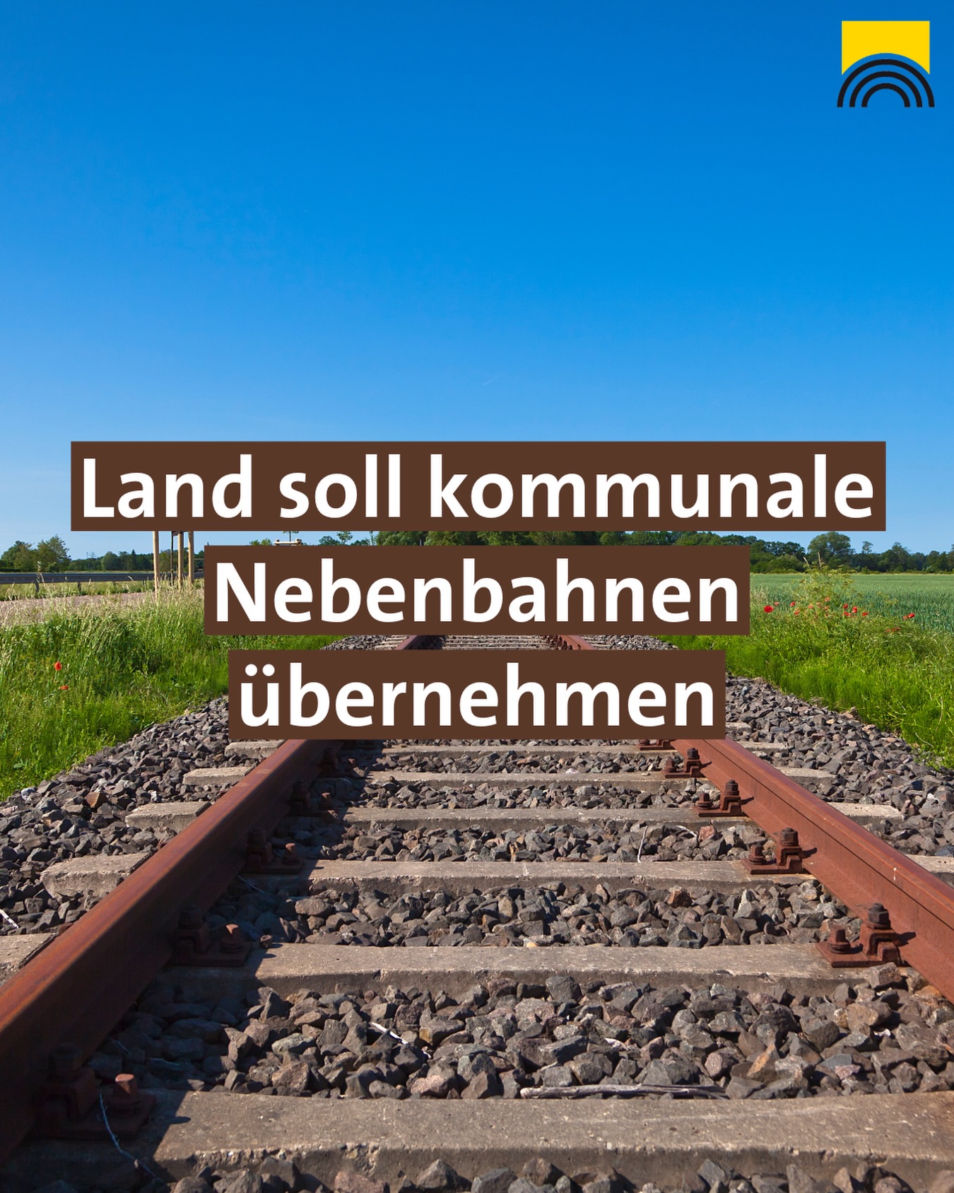 Dieser Alternativtext wurde KI-generiert: Ein Bahngleis führt in die Ferne, über einem Feld. Darüber befindet sich ein Textfeld mit Aufschrift in dunkler Farbe.