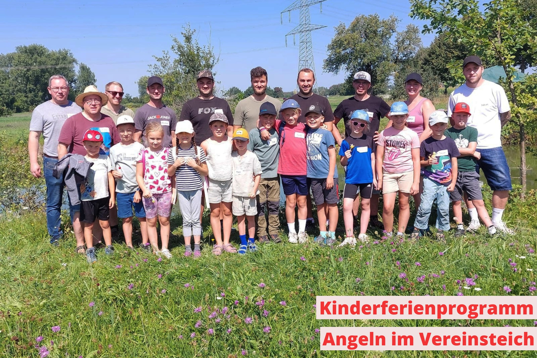 Eine Gruppe von Personen steht auf einem Feld vor Bäumen und Strommasten. Ein Banner mit rotem Text bewirbt ein Kinderferienprogramm mit dem Titel 'Angeln im Vereinsteich'.