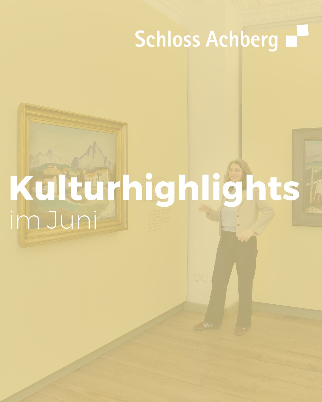 Eine Person steht in einem Ausstellungsraum neben einem gerahmten Gemälde mit Berglandschaft. Überlagert ist der Text „Schloss Achberg“ und „Kulturhighlights im Juni“. (KI-Alternativtext)
