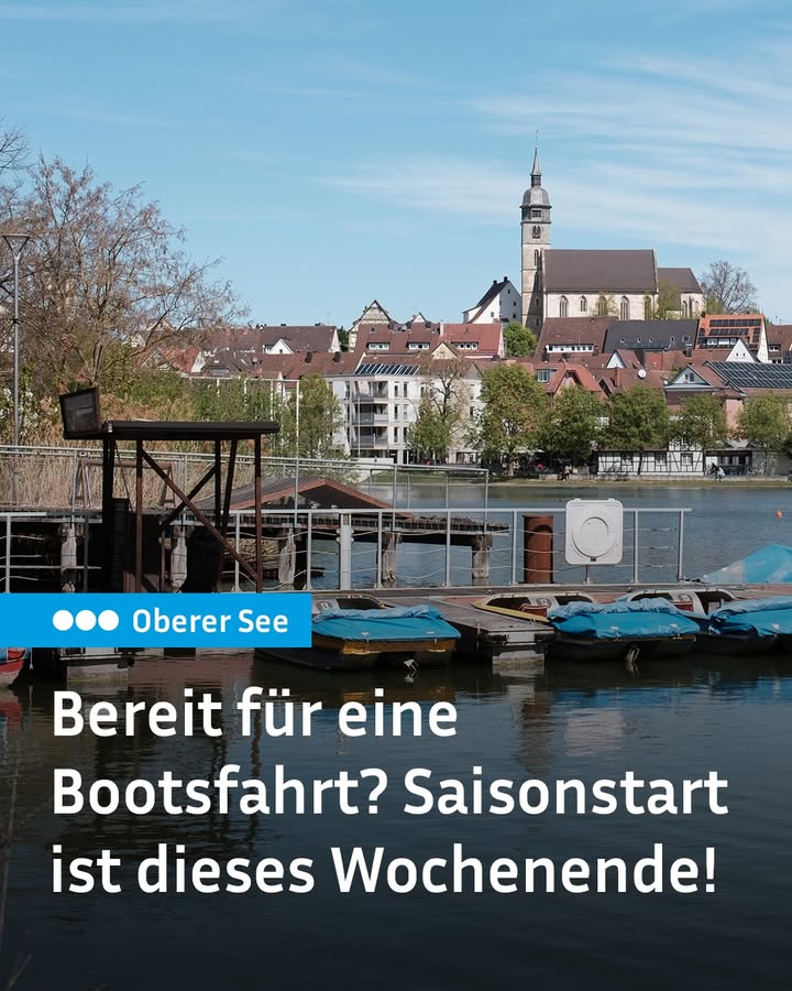 Dieser Alternativtext wurde KI-generiert: Ein See mit Booten im Vordergrund und einer Stadtlandschaft mit einem Kirchturm im Hintergrund. Das Bild ist farbig und zeigt eine werbliche Botschaft für Bootsfahrten.