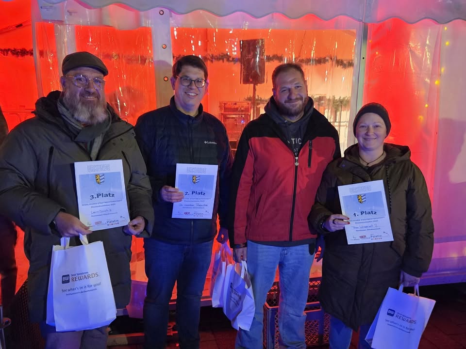 Dieser Alternativtext wurde KI-generiert: Eine Gruppe von Personen hält Urkunden in den Händen. Im Hintergrund sind Dekorationen und ein festlicher Rahmen erkennbar.