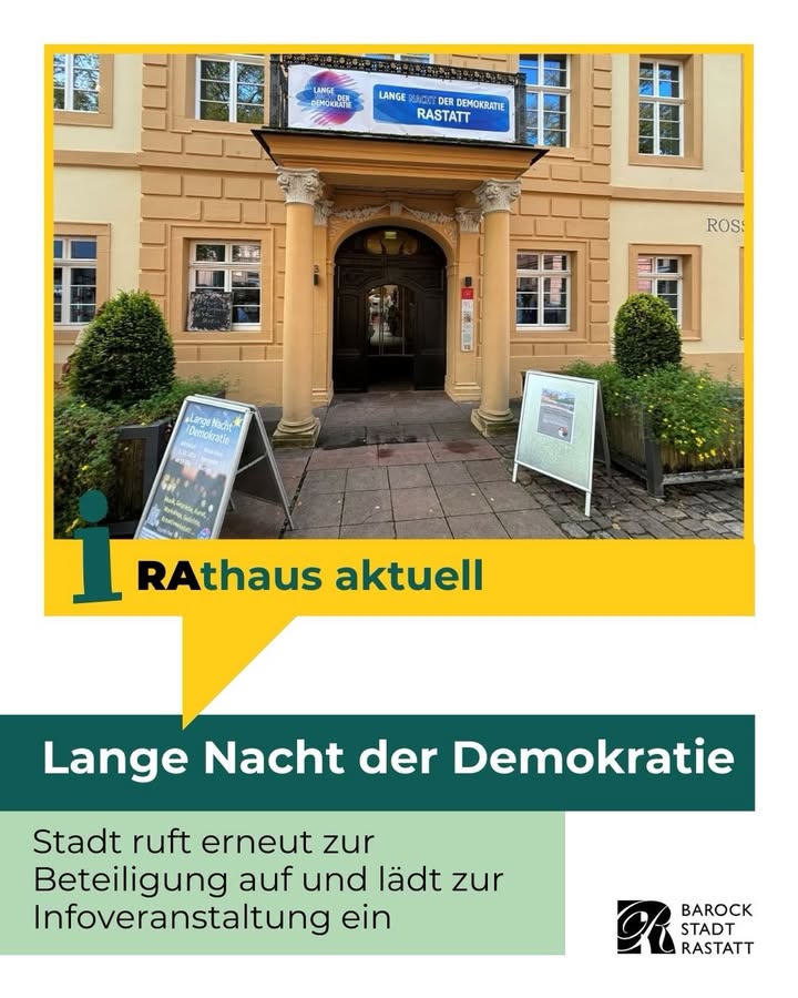 Dieser Alternativtext wurde KI-generiert: Ein helles Gebäude mit einer zentralen Eingangstür, über der ein Banner hängt. Vor dem Gebäude befinden sich Büsche und ein Informationsstand mit Texten und Logos.