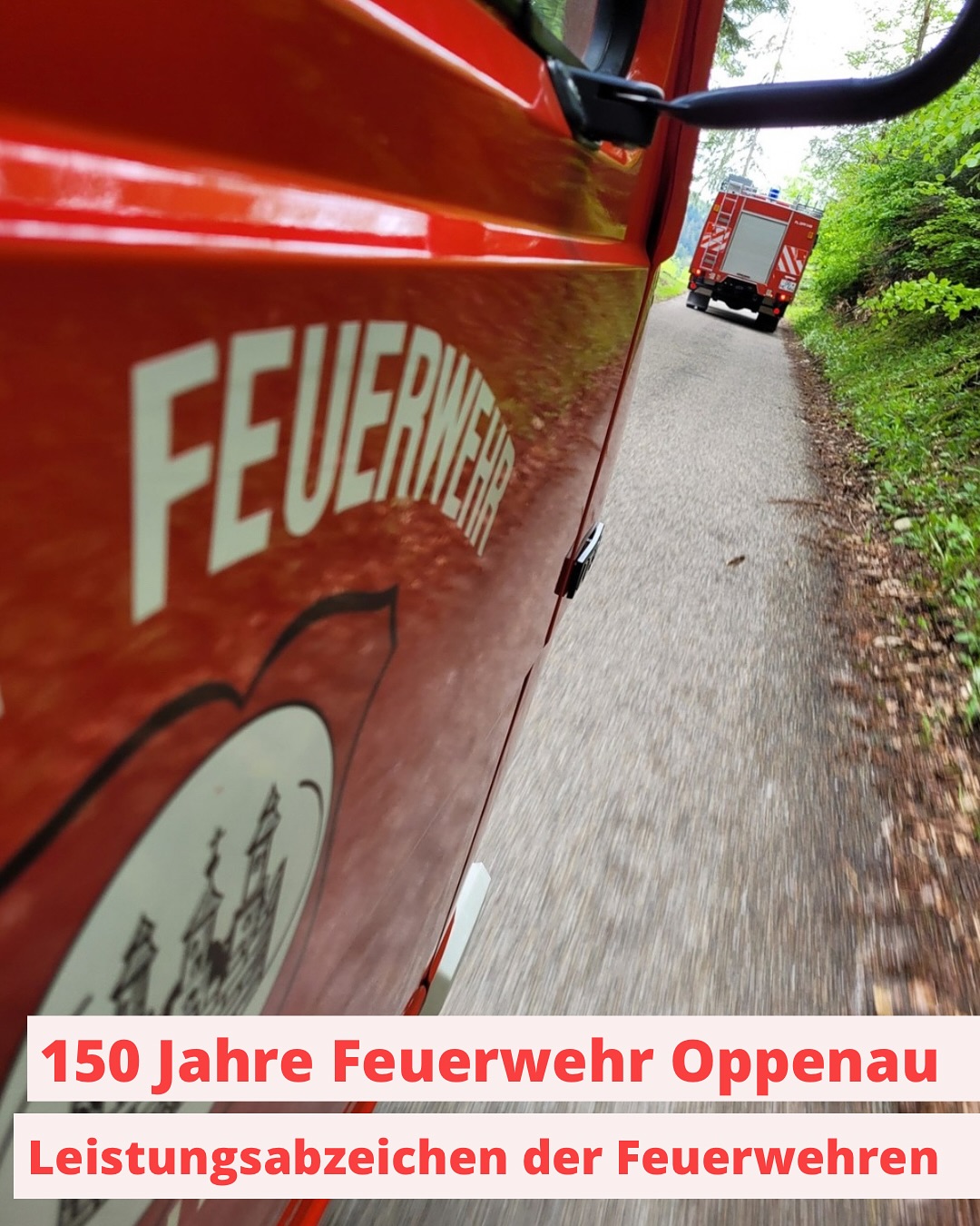 Ein rotes Feuerwehrfahrzeug mit der Aufschrift "Feuerwehr" steht am Straßenrand. Ein zweites rotes Feuerwehrfahrzeug fährt die Straße entlang.