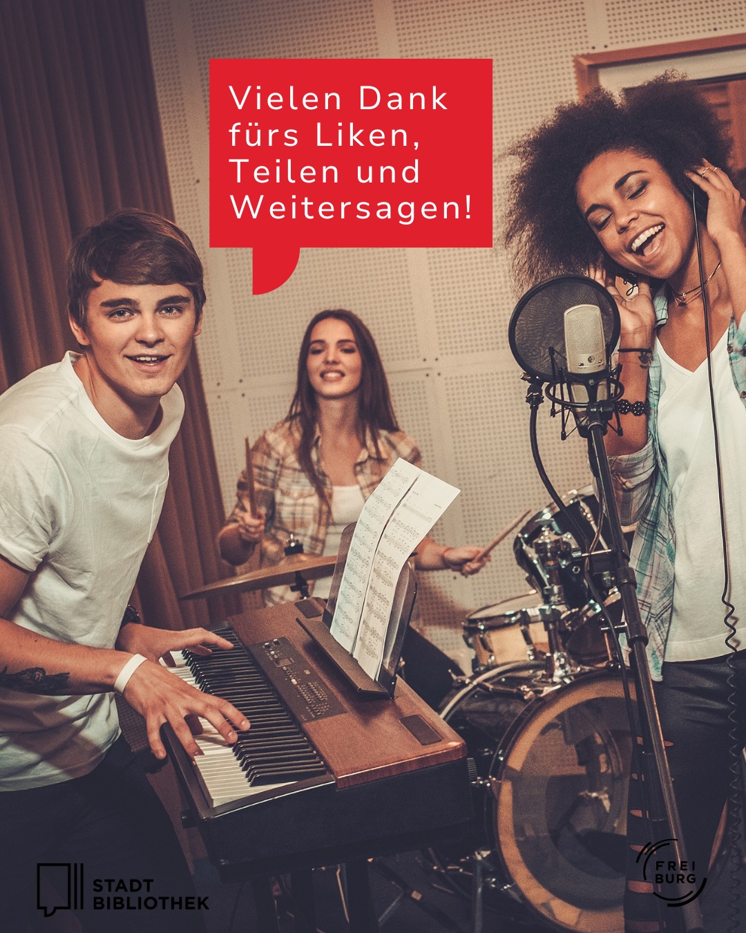 Drei Personen in einem Tonstudio: Eine spielt Keyboard, eine schlägt Schlagzeug, eine singt ins Mikrofon. Ein roter Textfeld sagt: „Vielen Dank fürs Liken, Teilen und Weitersagen!“ Unten links das Logo „Stadt Bibliothek“, rechts „Freiburg“. (KI-Alternativtext)