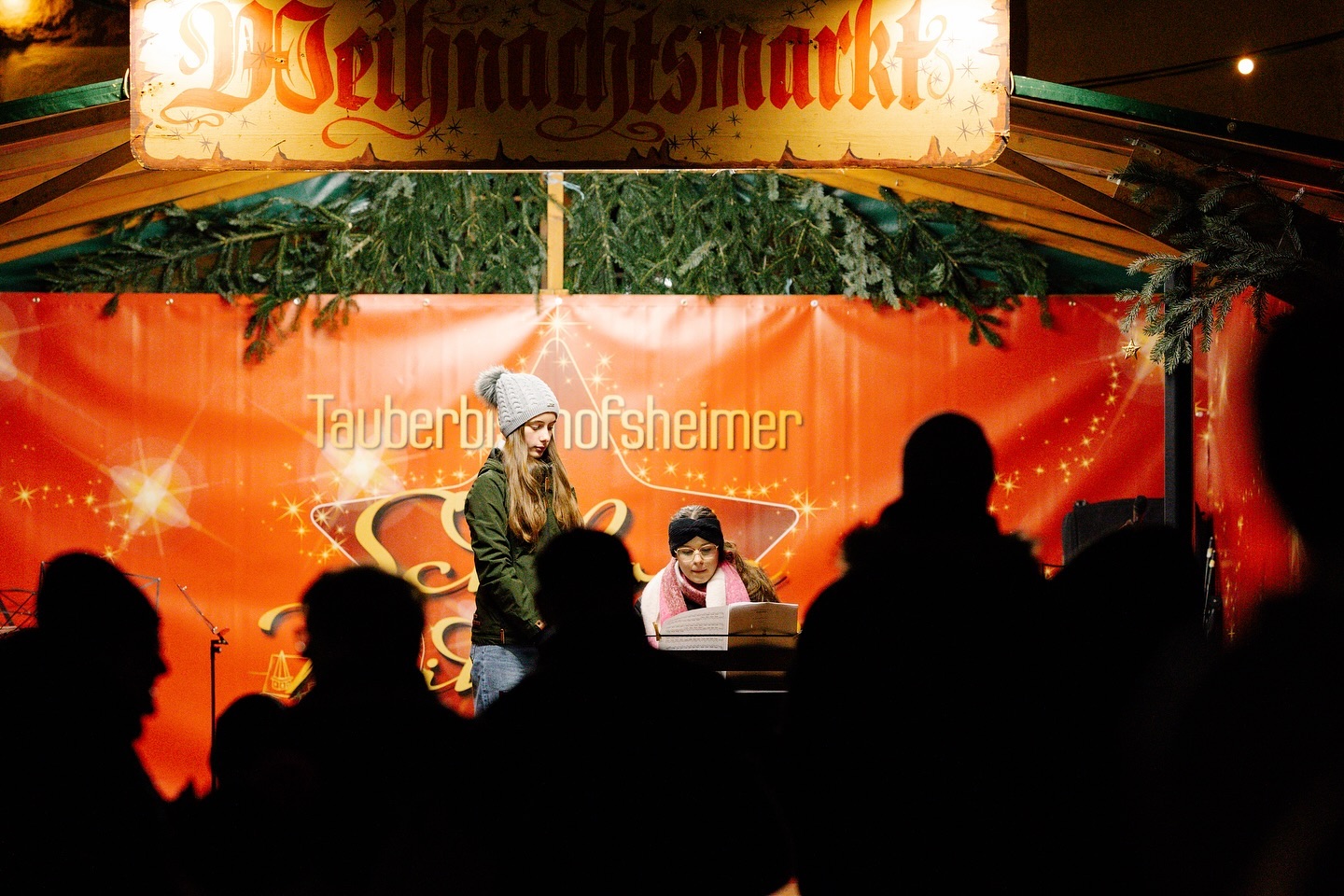 Musiker spielen auf einem Weihnachtsmarkt. Die Szene ist in dunklen Farben gehalten.