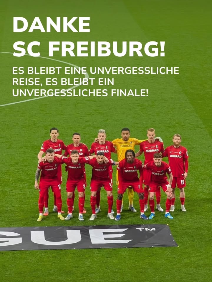 Elf Fußballspieler in roten Trikots und ein Torwart in gelbem Trikot posieren auf einem grünen Rasen vor einem Banner mit der Aufschrift „DANKE SC FREIBURG! ES BLEIBT EINE UNVERGESSLICHE REISE, ES BLEIBT EIN UNVERGESSLICHES FINALE!“. Ein Teil eines „UEFA“-Logos ist am Boden sichtbar. (KI-Alternativtext)