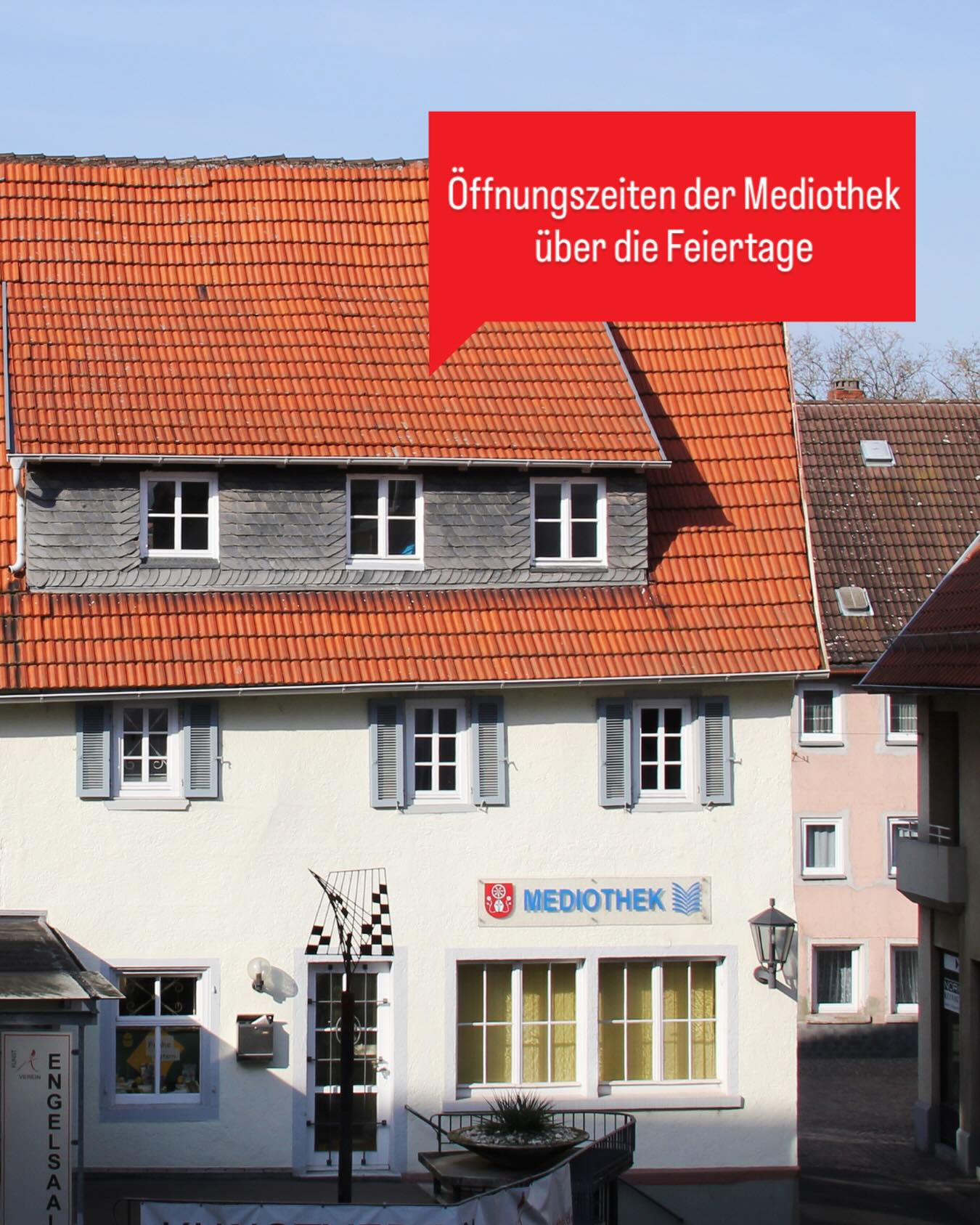 Dieser Alternativtext wurde KI-generiert: Ein Gebäude mit einem roten Dach und mehreren Fenstern. Ein Schild mit Aufschrift ist an der Fassade angebracht.
