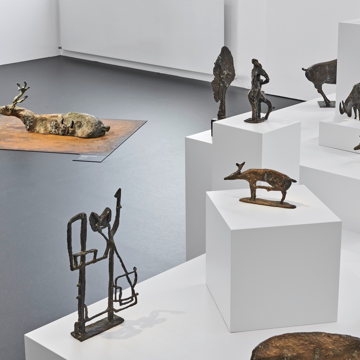 Dieser Alternativtext wurde KI-generiert: Mehrere Skulpturen, die scheinbar Tiere und Figuren darstellen, stehen auf weißen Sockeln in einem hellen Raum. Das Bild ist farbig und zeigt unterschiedliche Texturen und Formen.