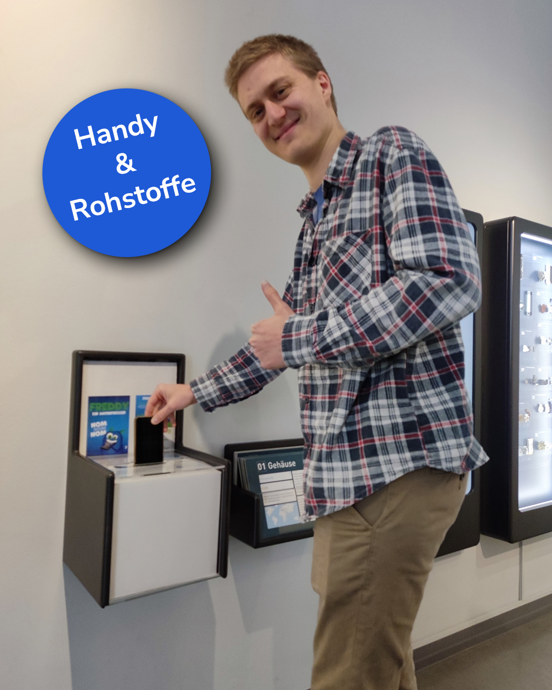 Dieser Alternativtext wurde KI-generiert: Eine Person zeigt auf einen Automaten in einem Innenraum. Im Hintergrund sind weitere Geräte und ein Schrank zu sehen.