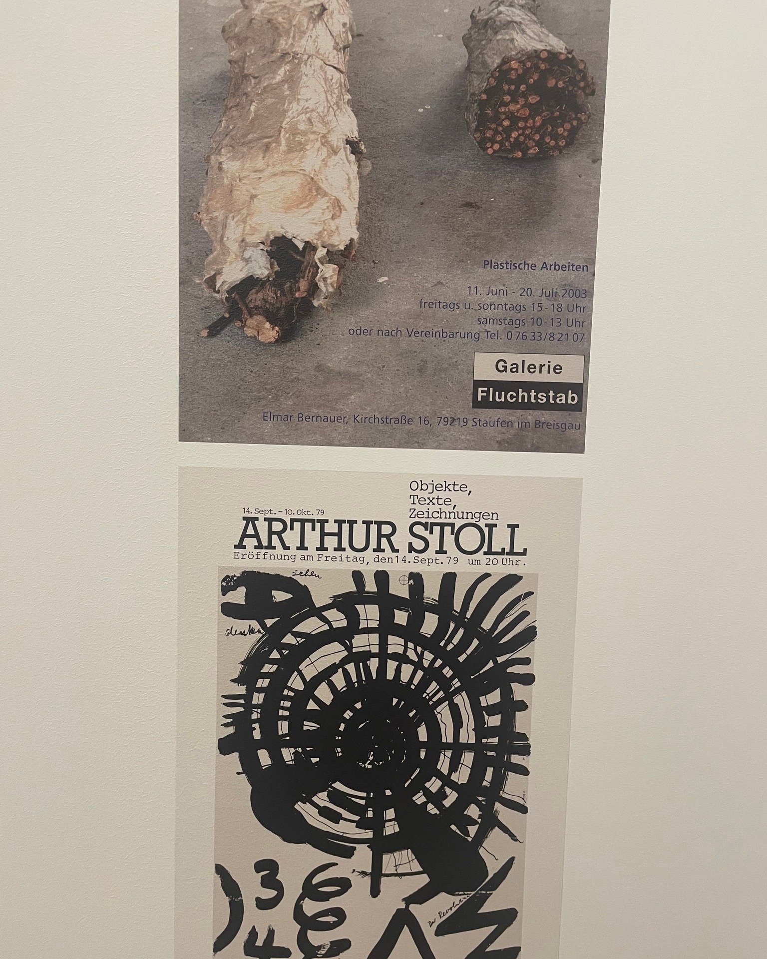 Dieser Alternativtext wurde KI-generiert: Schwarz-weißes Foto, das zwei Poster zeigt. Eines ist eine Ankündigung einer Ausstellung, das andere ein künstlerisches Werk mit abstrakten Formen.