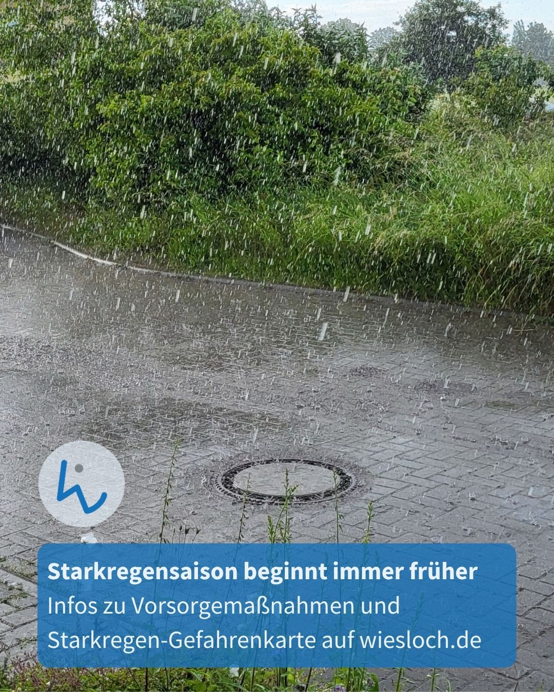 Starker Regen fällt auf einen gepflasterten Weg mit einem runden Schachtdeckel, im Hintergrund grüne Büsche. Ein blauer Textkasten informiert über die früher beginnende Starkregensaison und verweist auf Vorsorgemaßnahmen und eine Gefahrenkarte auf wiesloch.de. (KI-Alternativtext)