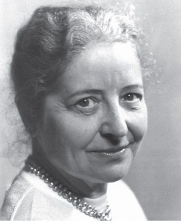 Dieser Alternativtext wurde KI-generiert: Schwarz-weißes Porträt einer Person mit kurzem, lockigem Haar und einem Halsband. Die Person blickt freundlich in die Kamera.