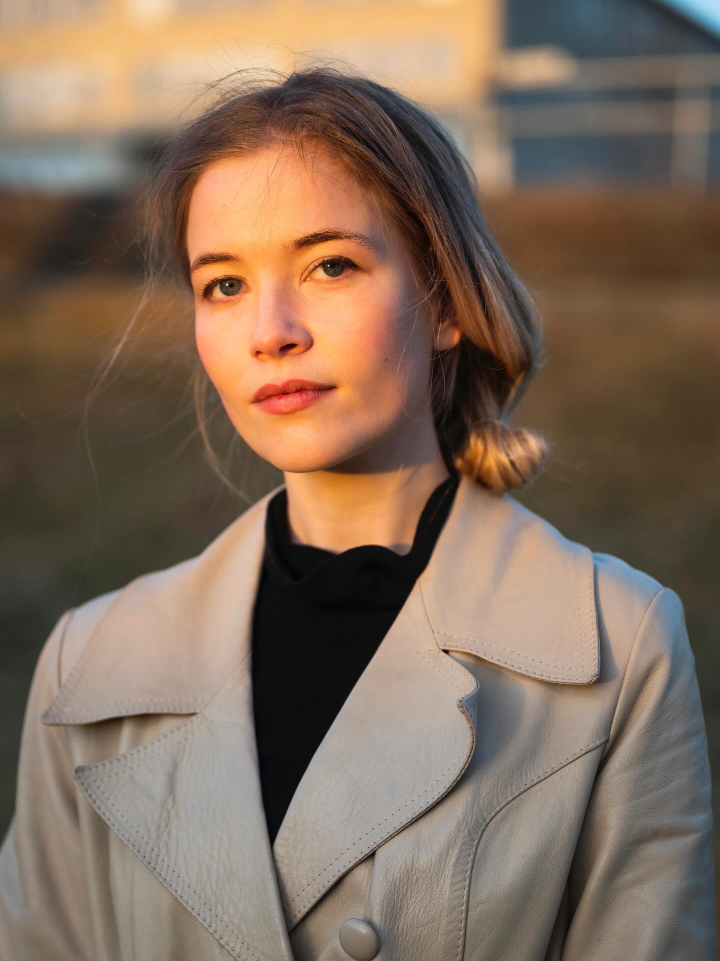 Dieser Alternativtext wurde KI-generiert: Porträt einer Person im Gegenlicht. Die Person trägt eine Jacke und blickt direkt in die Kamera.