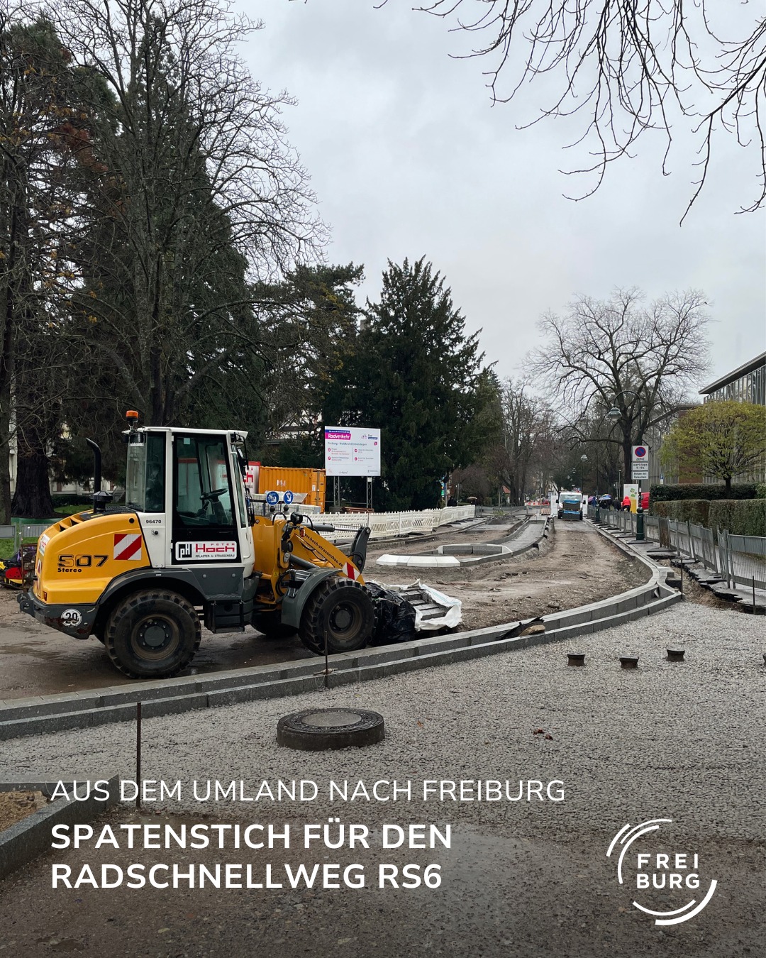 Dieser Alternativtext wurde KI-generiert: Ein Schwarz-Weiß-Foto zeigt eine Baustelle mit einem großen gelben Fahrzeug und aufgebrochenem Pflaster. Im Hintergrund sind Bäume und ein Zaun zu sehen.