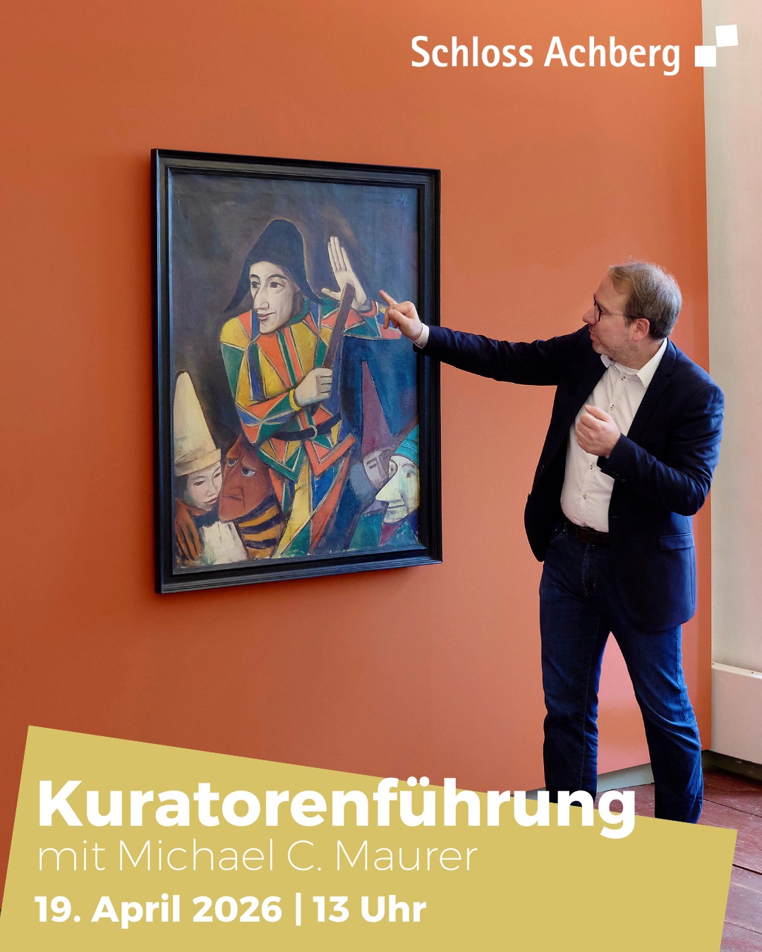 Dieser Alternativtext wurde KI-generiert: Ein Gemälde mit Figuren im Stil des Kubismus hängt an einer orangefarbenen Wand. Eine Person steht daneben und deutet auf das Kunstwerk.