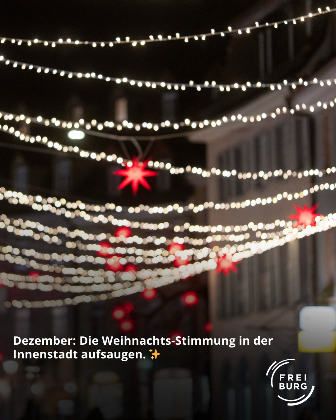 Dieser Alternativtext wurde KI-generiert: Eine unscharfe Aufnahme von hellen Lichtern, die eine Dekoration mit roten Elementen beleuchten. Das Bild ist vertikal und in Farbe gehalten.