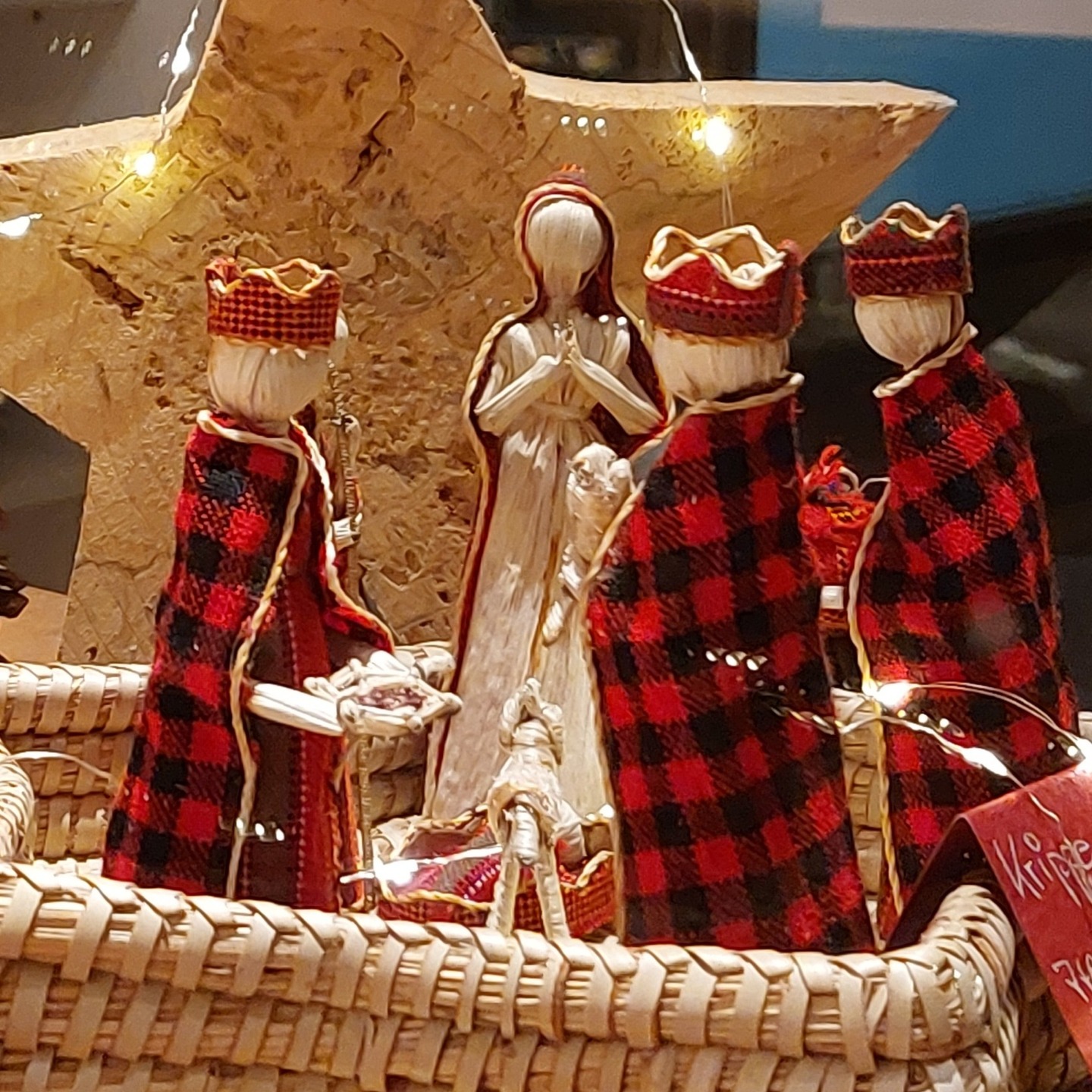 Dieser Alternativtext wurde KI-generiert: Mehrere Figuren in roten und weißen Gewändern stehen nebeneinander. Sie befinden sich vor einer strohbedeckten Kulisse mit saisonaler Dekoration.